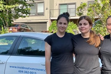 Three women wearing matching black shirts stand in front of a white car with InsideOut Cleaning Services and contact information on the side, highlighting cleaners Vancouver, with houses and greenery in the background.
